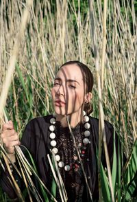 Portrait of young woman standing amidst grass