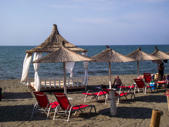 Chairs on beach by sea against sky