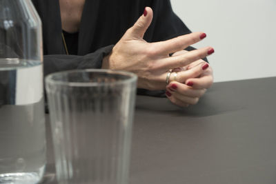 Midsection of woman holding wedding ring in finger while sitting by table