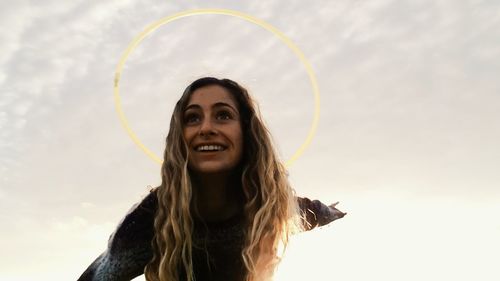 Portrait of smiling young woman against sky