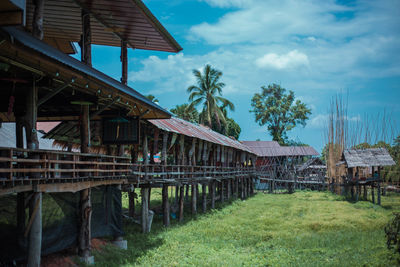 Built structure on field by houses against sky