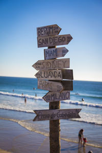 Information sign on beach against clear sky