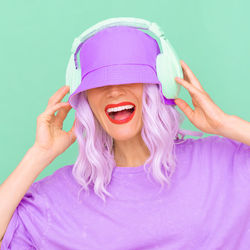 Side view of woman wearing hat and headphones against colored background