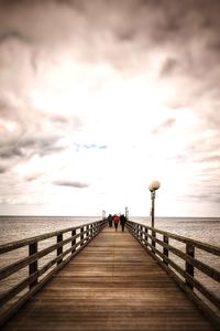 Pier over sea against sky during sunset