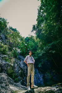 Full length of young man standing on rock against trees