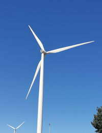 Low angle view of wind turbine against blue sky