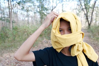 Portrait of woman covering face with scarf in forest