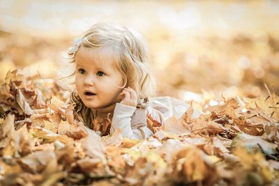 Cute girl lying on dry leaves during autumn