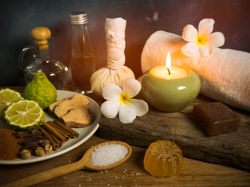 Close-up of ingredients and lit candle on table