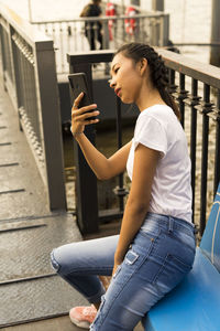 Side view of young woman using mobile phone