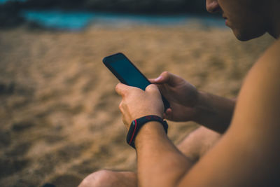 Midsection of man using mobile phone at beach