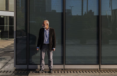 Portrait of adult man in suit against glass wall