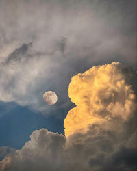 Low angle view of cloudscape against sky at sunset and moon