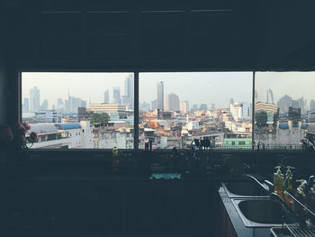 Buildings in city against sky seen through window