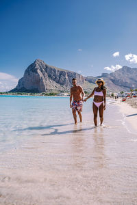 People on beach by mountain against sky