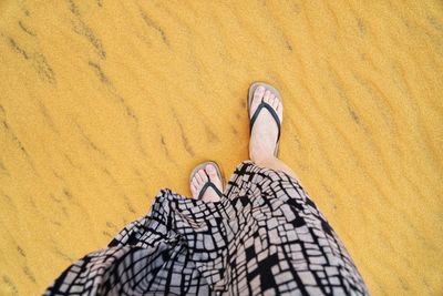 Low section of woman walking on sand at beach