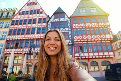 Portrait of smiling young woman against building