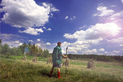 Man standing on grassy field against cloudy sky