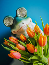 Close-up of tulips in vase against blue background