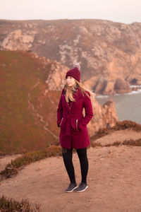 Full length of woman standing on cliff against mountain ranges