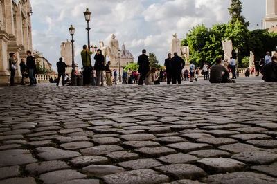 People on cobblestone street against sky