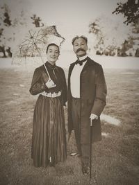 Portrait of well dressed couple standing on field