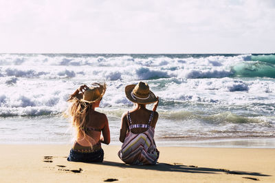Rear view of women sitting on beach
