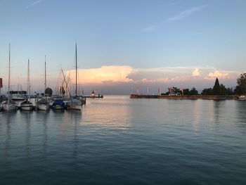 Sailboats in sea at sunset