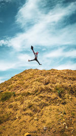 Man jumping over mountain against sky