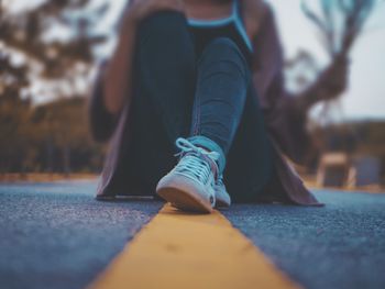 Low section of woman sitting on road