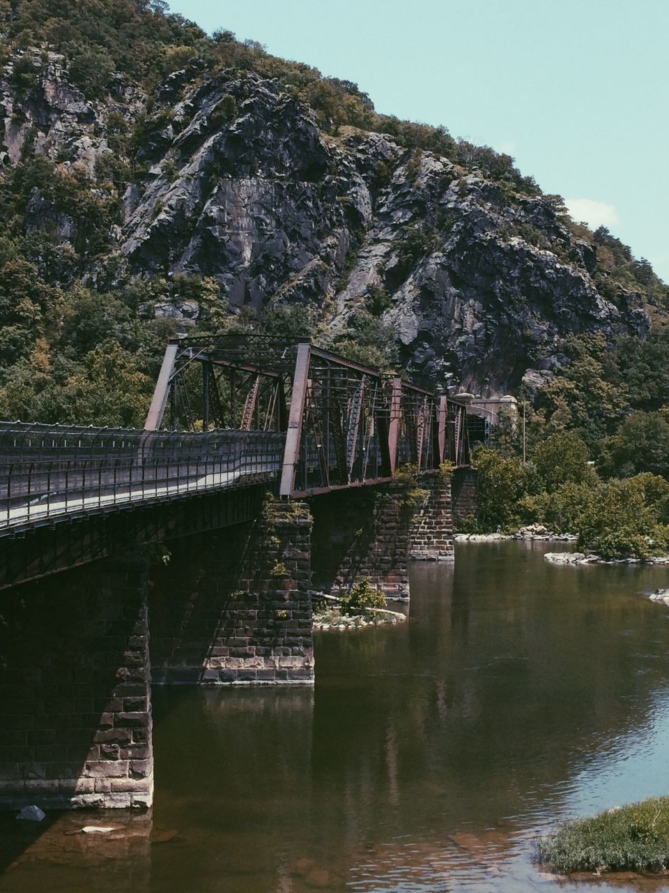 water, mountain, tree, built structure, architecture, tranquility, lake, river, tranquil scene, bridge - man made structure, scenics, nature, connection, beauty in nature, clear sky, waterfront, reflection, day, travel destinations, sky