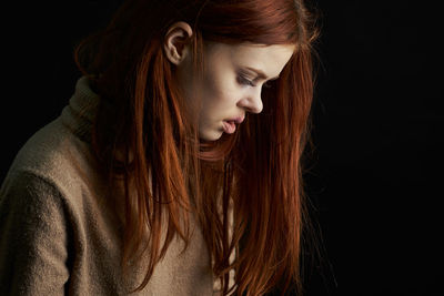 Portrait of young woman against black background