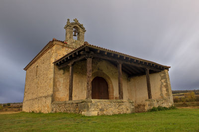 Low angle view of old building on field against sky