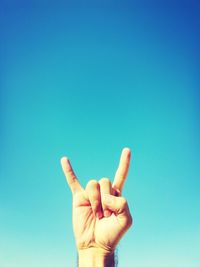 Close-up of human hand gesturing against clear blue sky