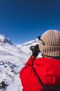 Rear view of man on snowcapped mountains against clear blue sky