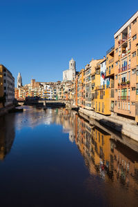 Canal by buildings against blue sky