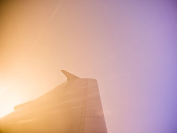 Low angle view of airplane flying against sky during sunset