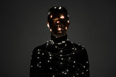 Man with illuminated string lights against gray background
