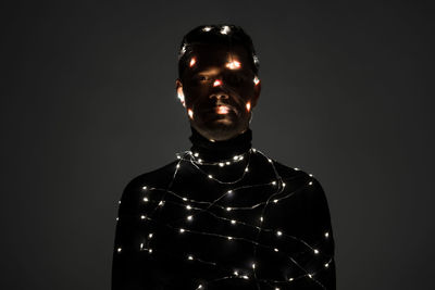 Close-up of illuminated man against black background