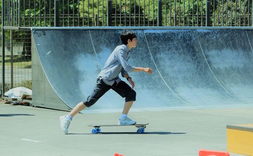 Full length of teenage boy skateboarding at park