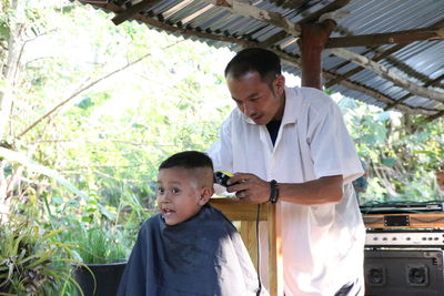 Barber cutting boy hair at shop