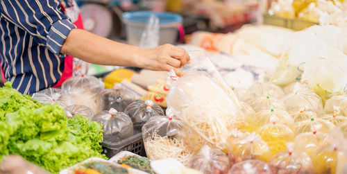 The female hand seller arranges the packaging of vegetables on the shelf and preparing to sell.