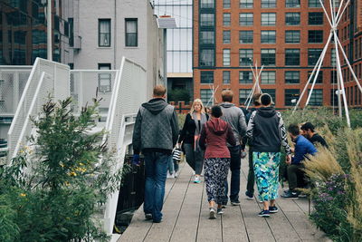 Rear view of people walking on street in city