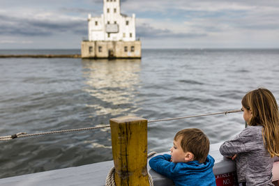 Children looking at lighthouse on cloudy day