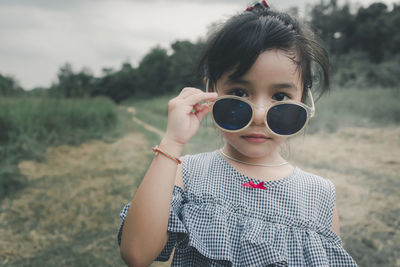 Portrait of boy holding sunglasses on field