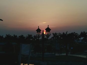 Silhouette temple against building during sunset