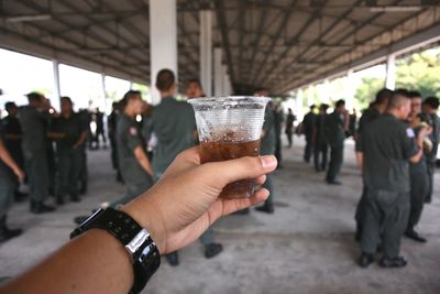 Cropped hand of man holding juice under bridge