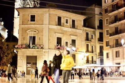 People walking against buildings in city at night