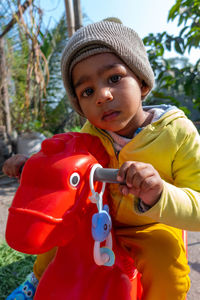 Portrait of cute boy wearing knit hat sitting on toy outdoors