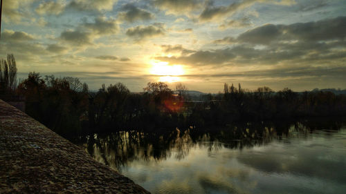 Scenic view of river against sky at sunset